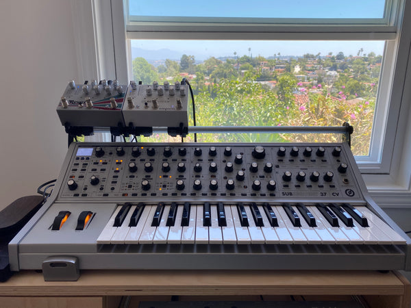 Two effects pedals held above Moog Subsequent 37 by a KVgear SubPiggy stand